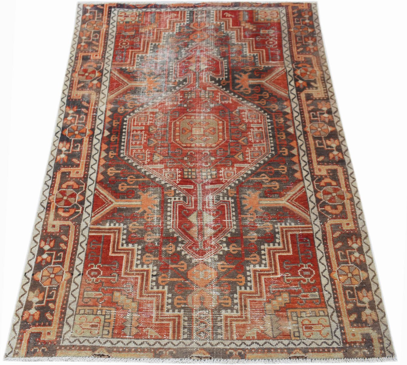 A handwoven vintage Persian rug featuring a geometric medallion pattern in shades of red and brown.