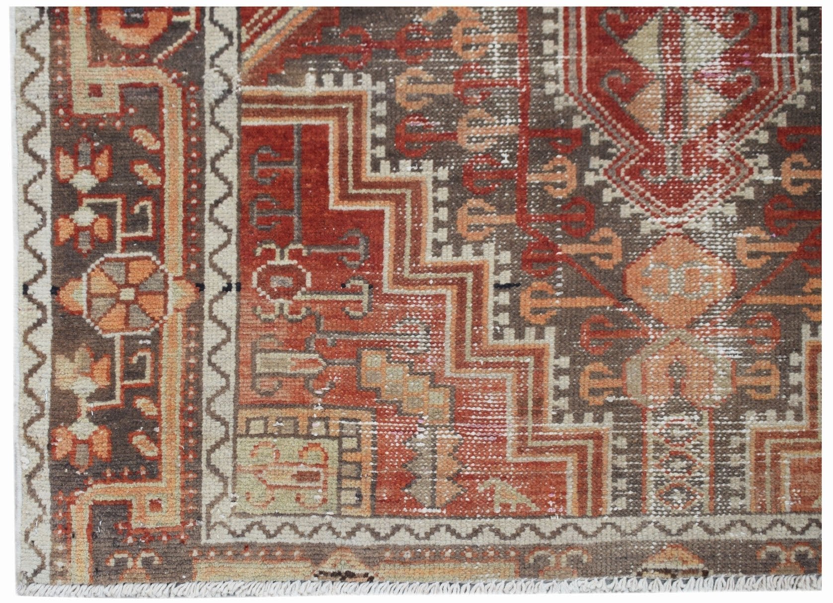 A handwoven vintage Persian rug featuring geometric patterns in shades of red, brown, and cream.