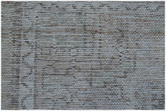 A close-up view of a handwoven vintage Persian rug featuring a faded, distressed geometric pattern.