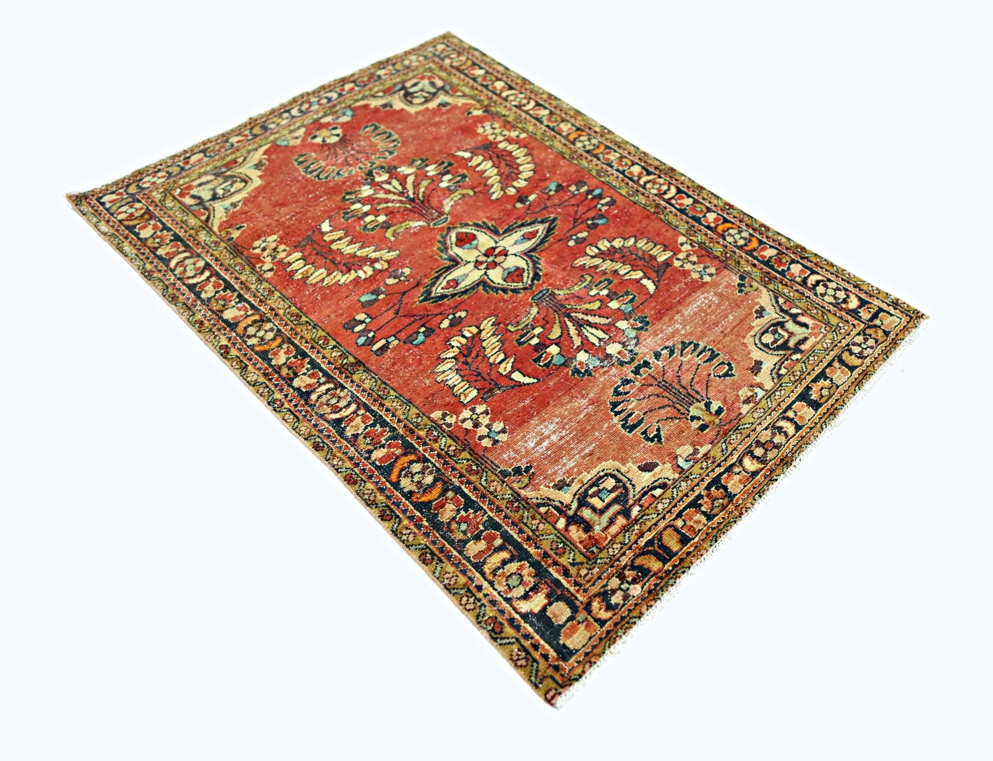 A vintage handmade Persian rug featuring a central floral motif on a faded red background.