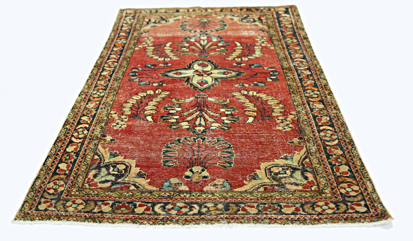 A vintage handmade Persian rug featuring a floral pattern in red, cream, and blue tones.