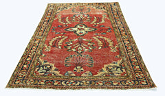 A vintage handmade Persian rug featuring a floral pattern in red, cream, and blue tones.