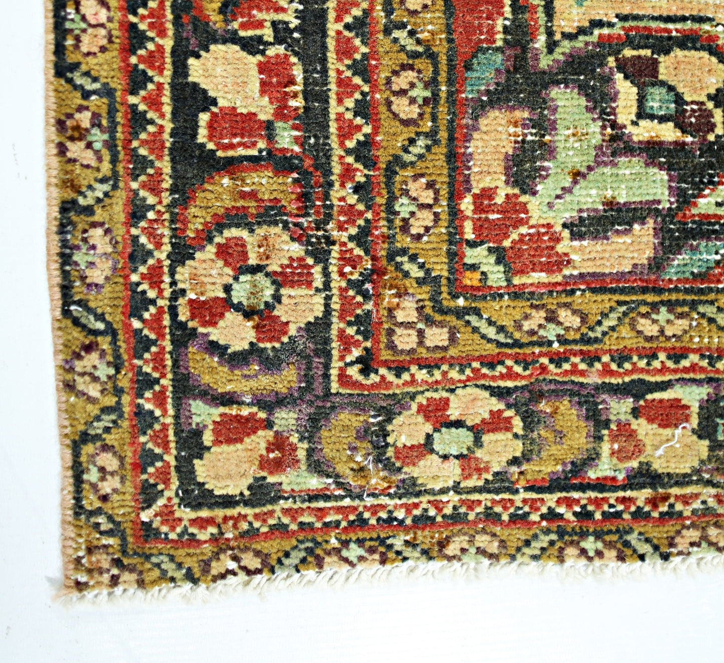 A corner view of a handmade vintage Persian rug featuring intricate floral patterns in warm tones.