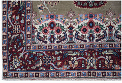 A vintage handwoven Persian rug featuring intricate floral and bird motifs in red and olive tones.