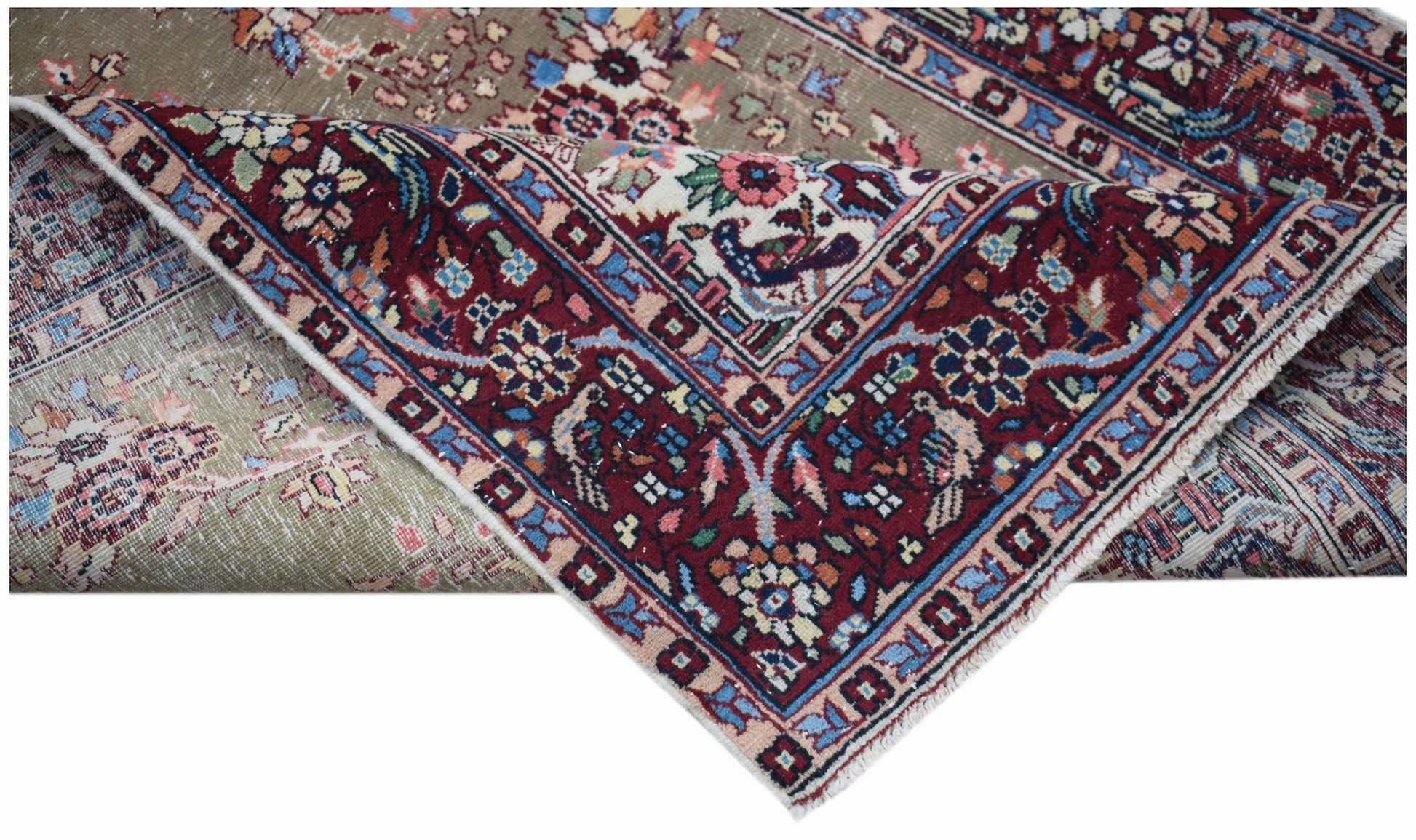 A handwoven vintage Persian rug with a red floral border folded over a muted taupe field.