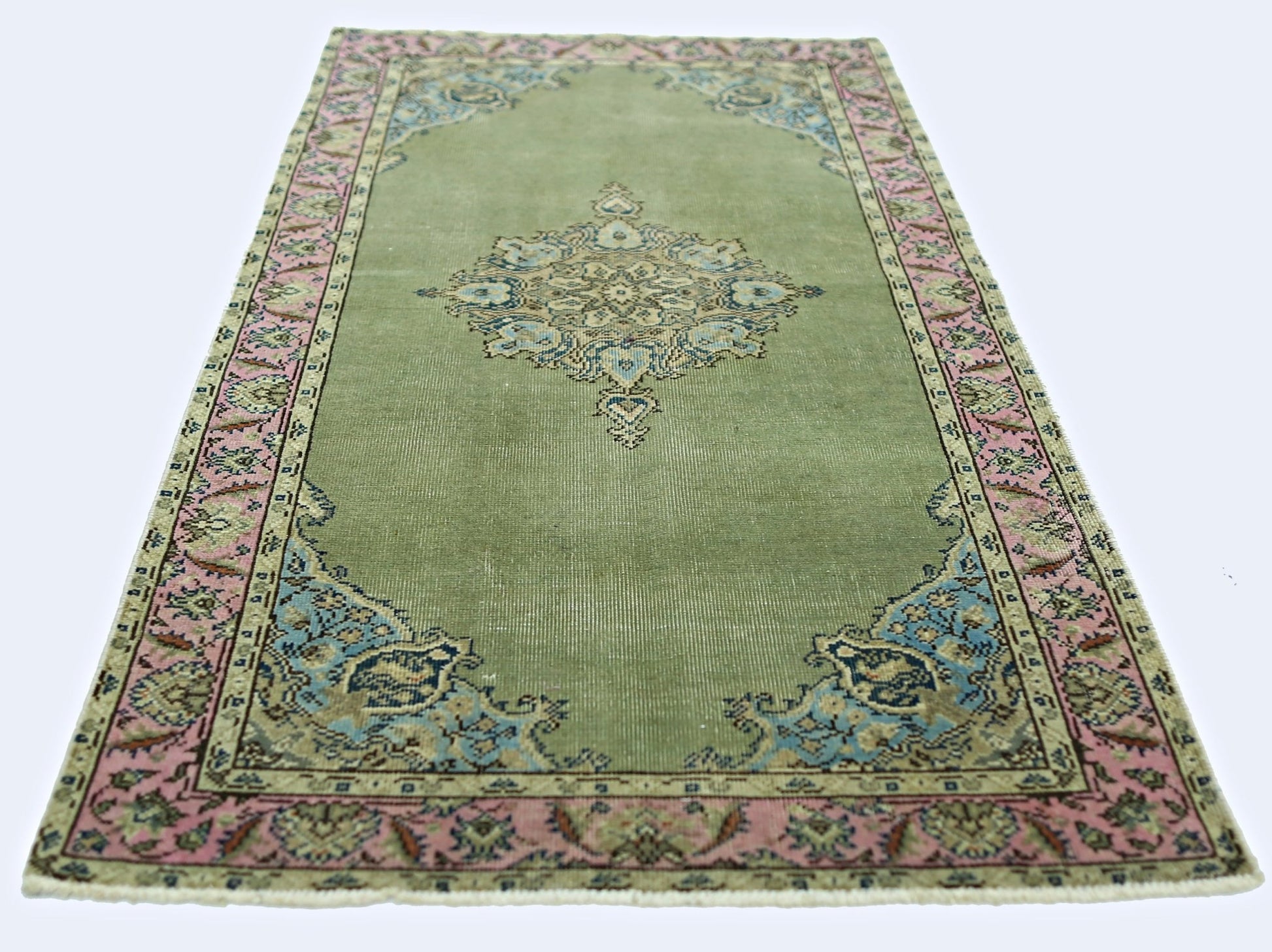 A vintage handmade Persian rug featuring a central floral medallion on a sage green field.
