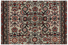 A vintage handwoven Persian rug featuring a detailed geometric floral pattern in red and black.