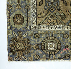 A vintage Persian rug featuring intricate geometric patterns in shades of blue, brown, and cream.