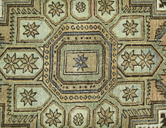 A vintage Persian rug featuring a geometric pattern of octagons and star motifs in muted tones.