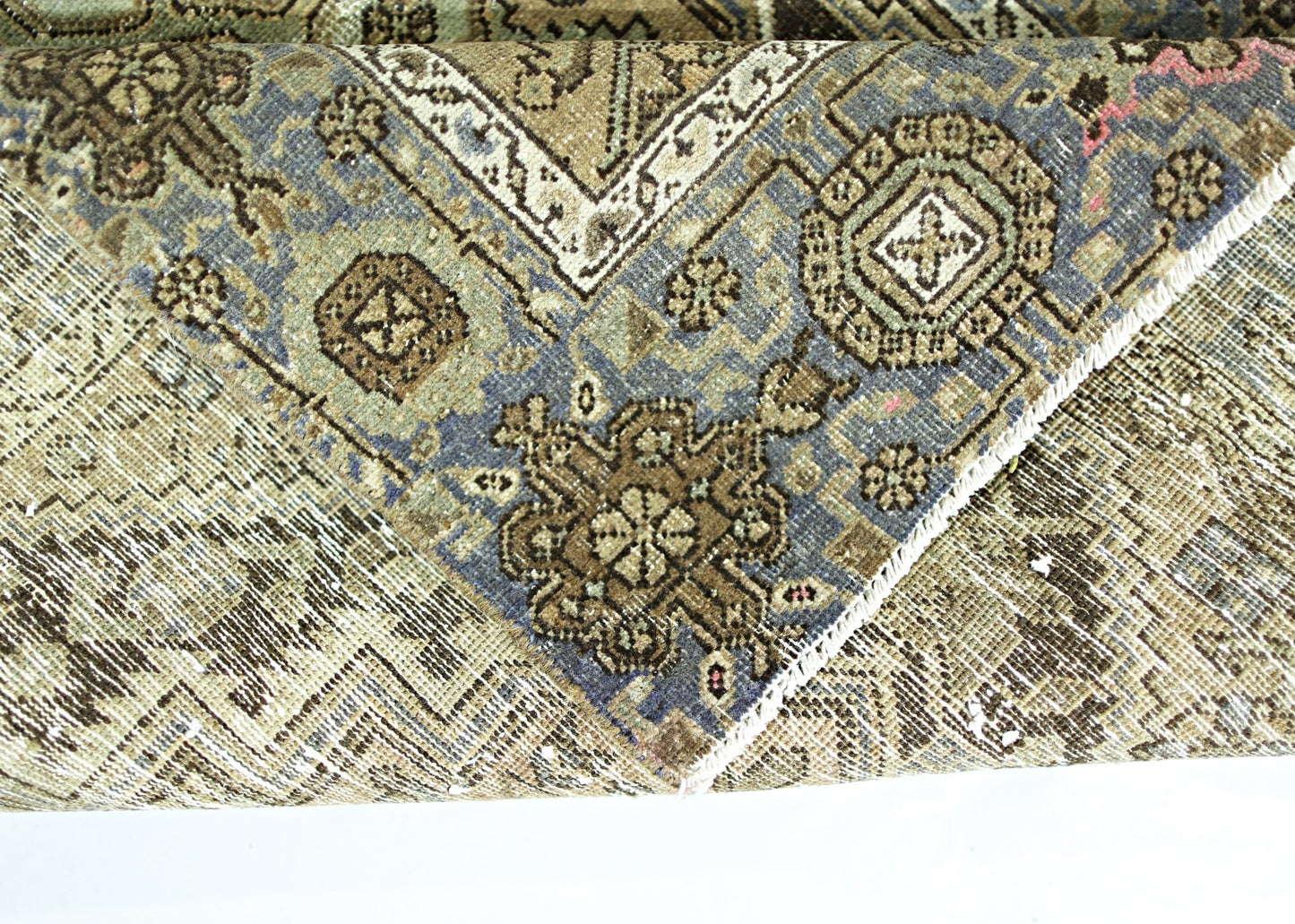 A folded vintage Persian rug featuring intricate geometric patterns in blue and brown tones.