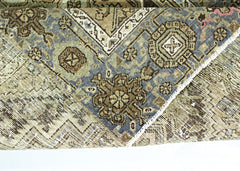 A folded vintage Persian rug featuring intricate geometric patterns in blue and brown tones.