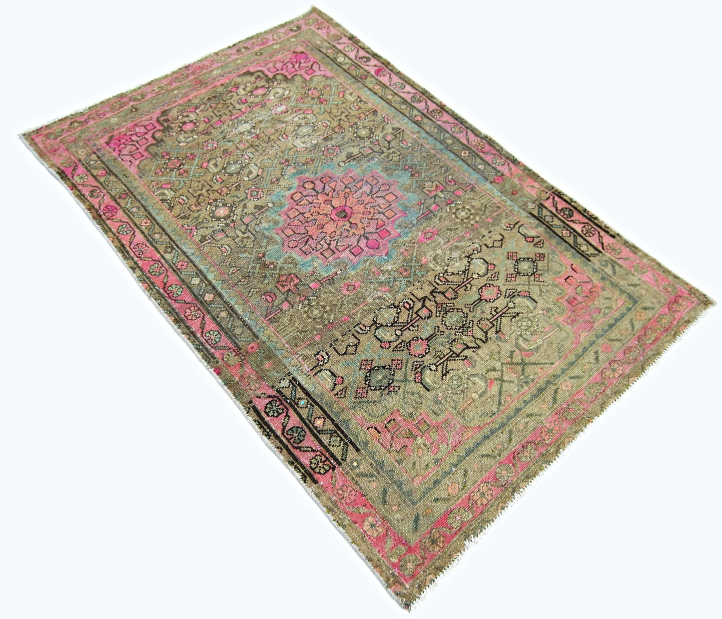 A vintage handmade Persian rug featuring a central floral medallion in pink and blue on a tan field.