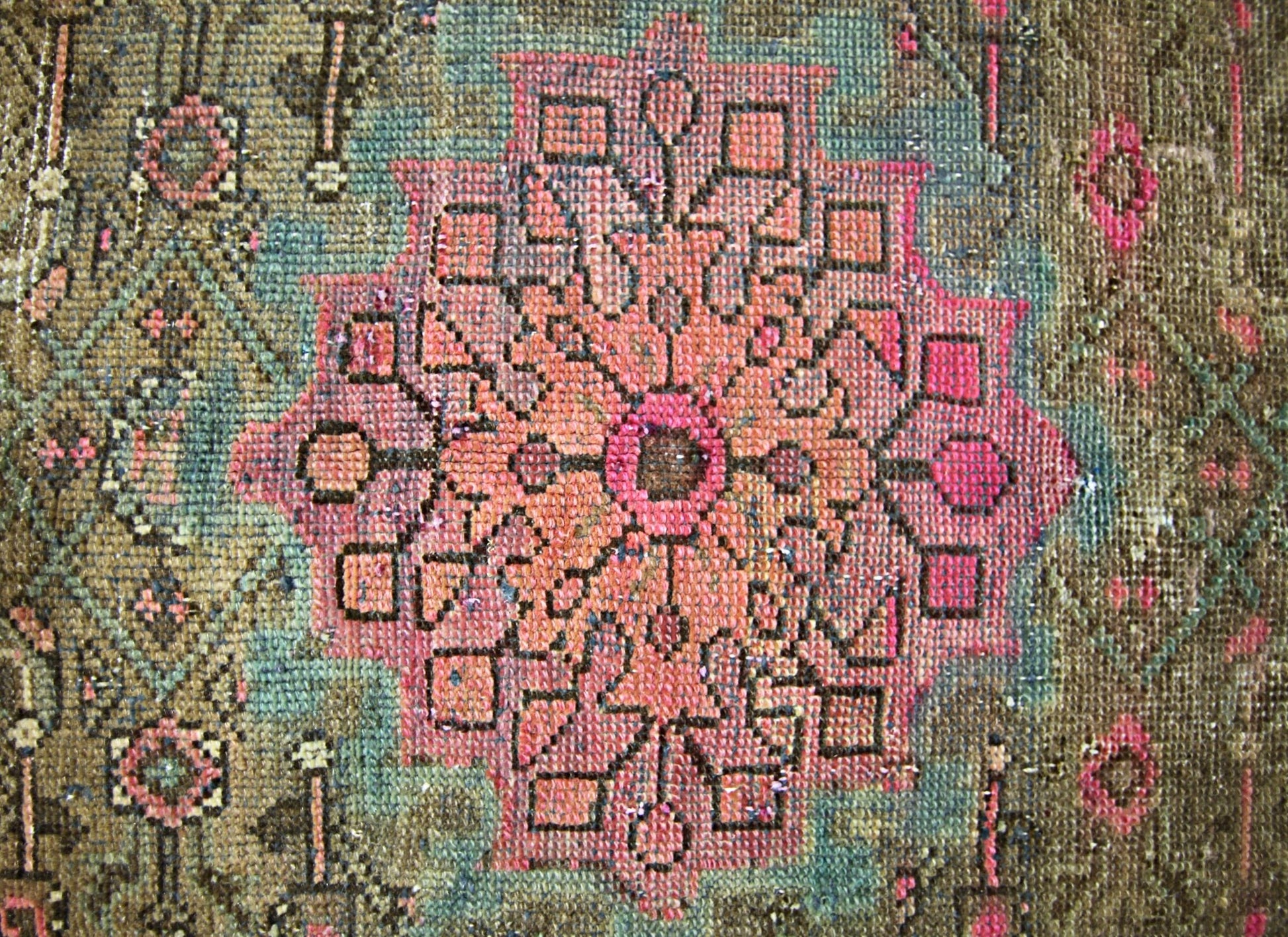 A vintage handmade Persian rug featuring a central pink floral medallion on a brown background.