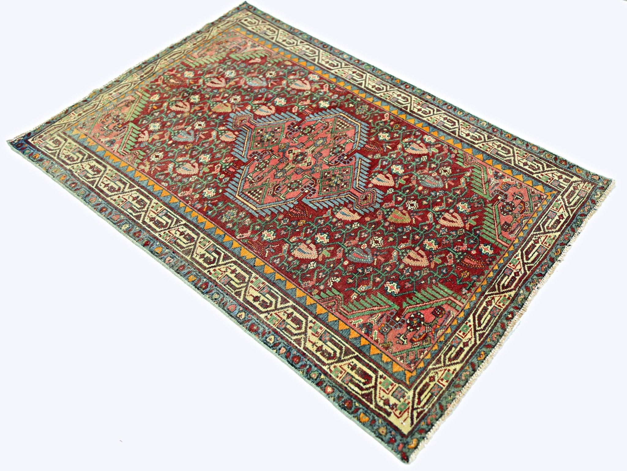 A vintage handmade Persian rug featuring a central medallion and floral patterns on a red field.