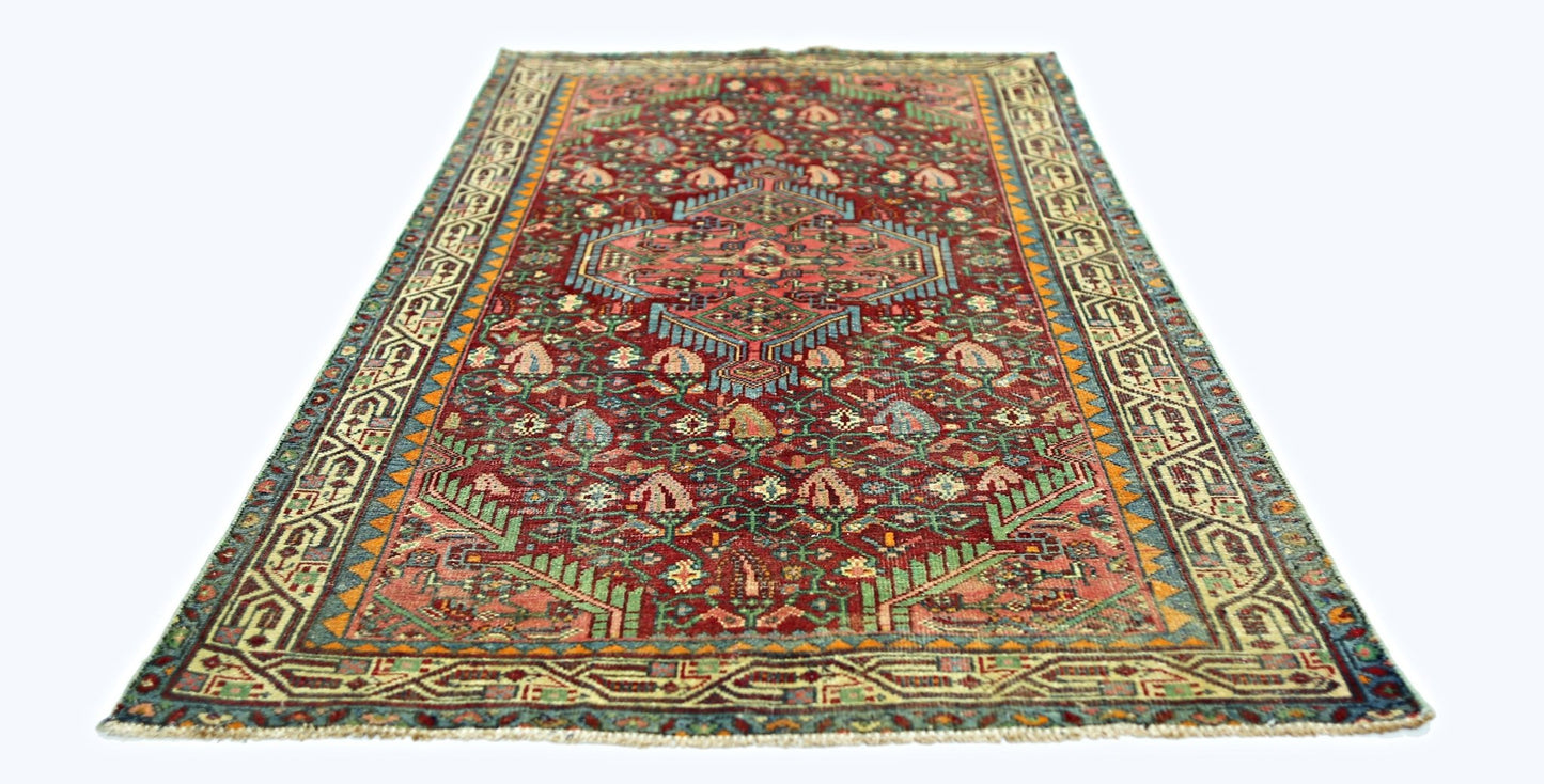 A rectangular vintage Persian rug with a red field, intricate floral patterns, and geometric borders.