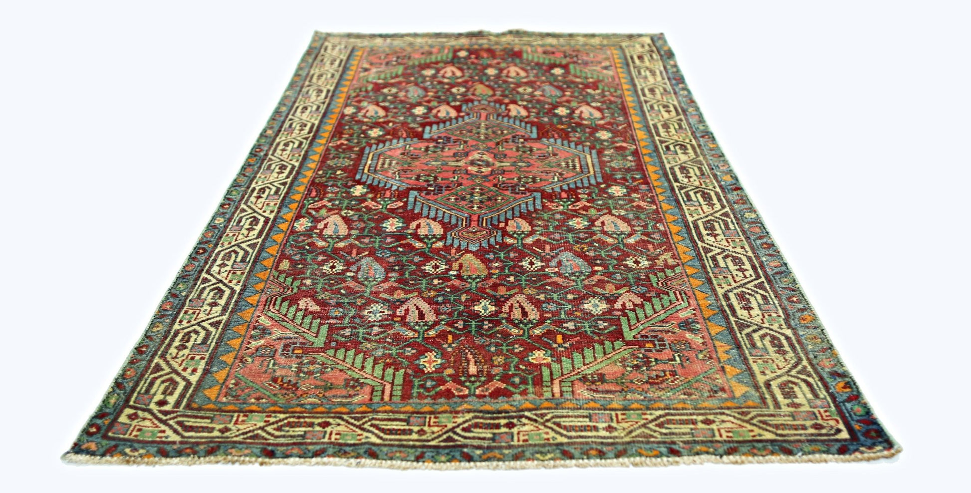 A rectangular vintage Persian rug with a red field, intricate floral patterns, and geometric borders.