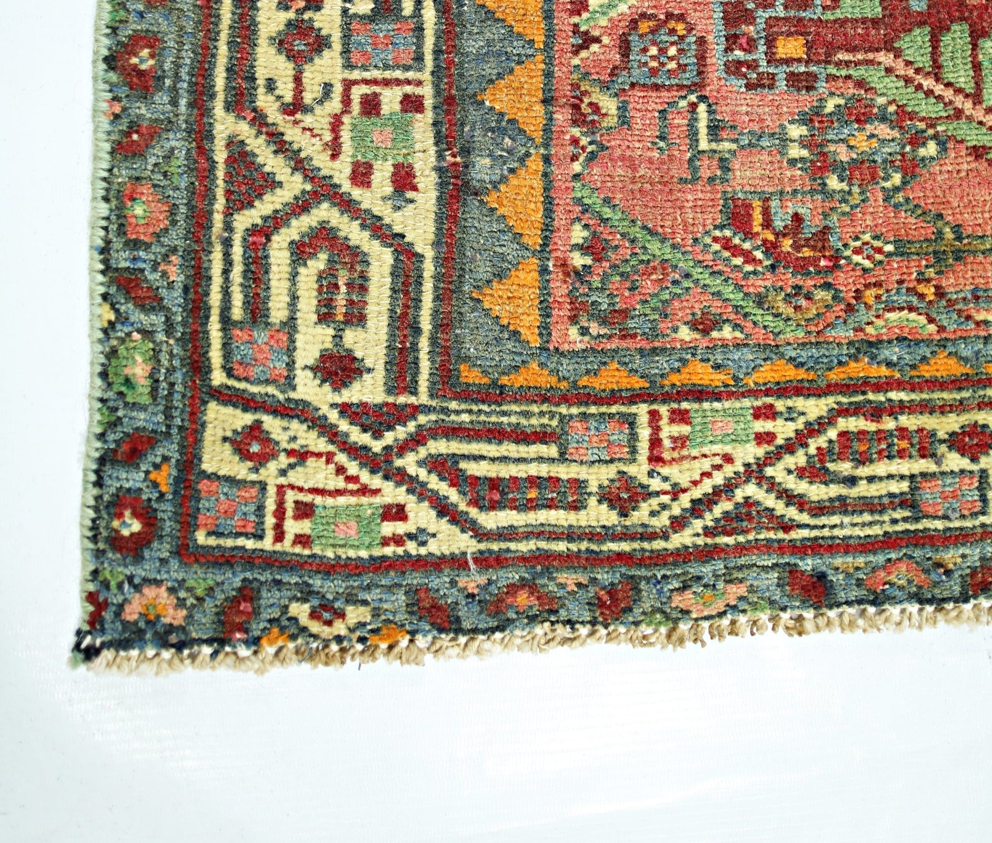 A corner view of a handmade vintage Persian rug featuring intricate geometric patterns in wool.