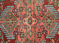 A vintage handmade Persian rug featuring intricate geometric patterns in red, blue, and green.