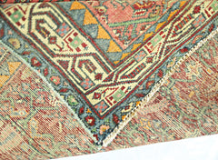 A corner of a vintage handmade Persian rug showing intricate geometric patterns in red, blue, and gold.