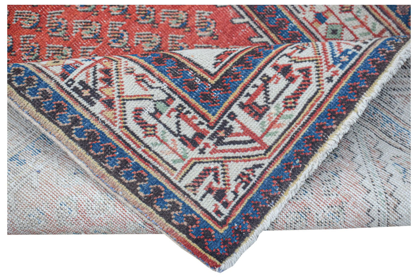 Vintage Persian rug with intricate geometric patterns in red, blue, and cream.