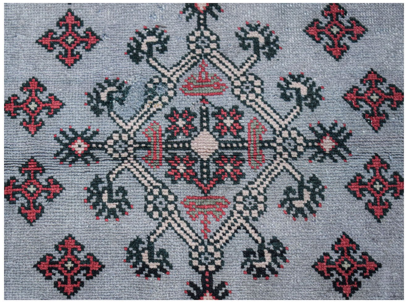 A vintage Persian rug featuring a central geometric medallion in red, black, and beige on grey.