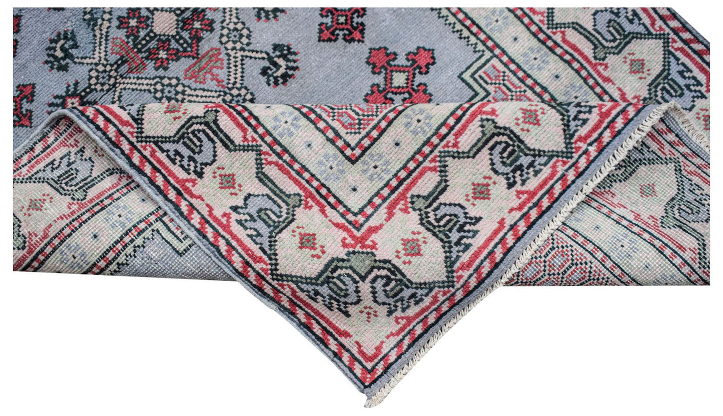 A vintage handwoven Persian rug featuring a blue field with red and cream geometric patterns.
