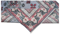 A vintage handwoven Persian rug featuring a blue field with red and cream geometric patterns.