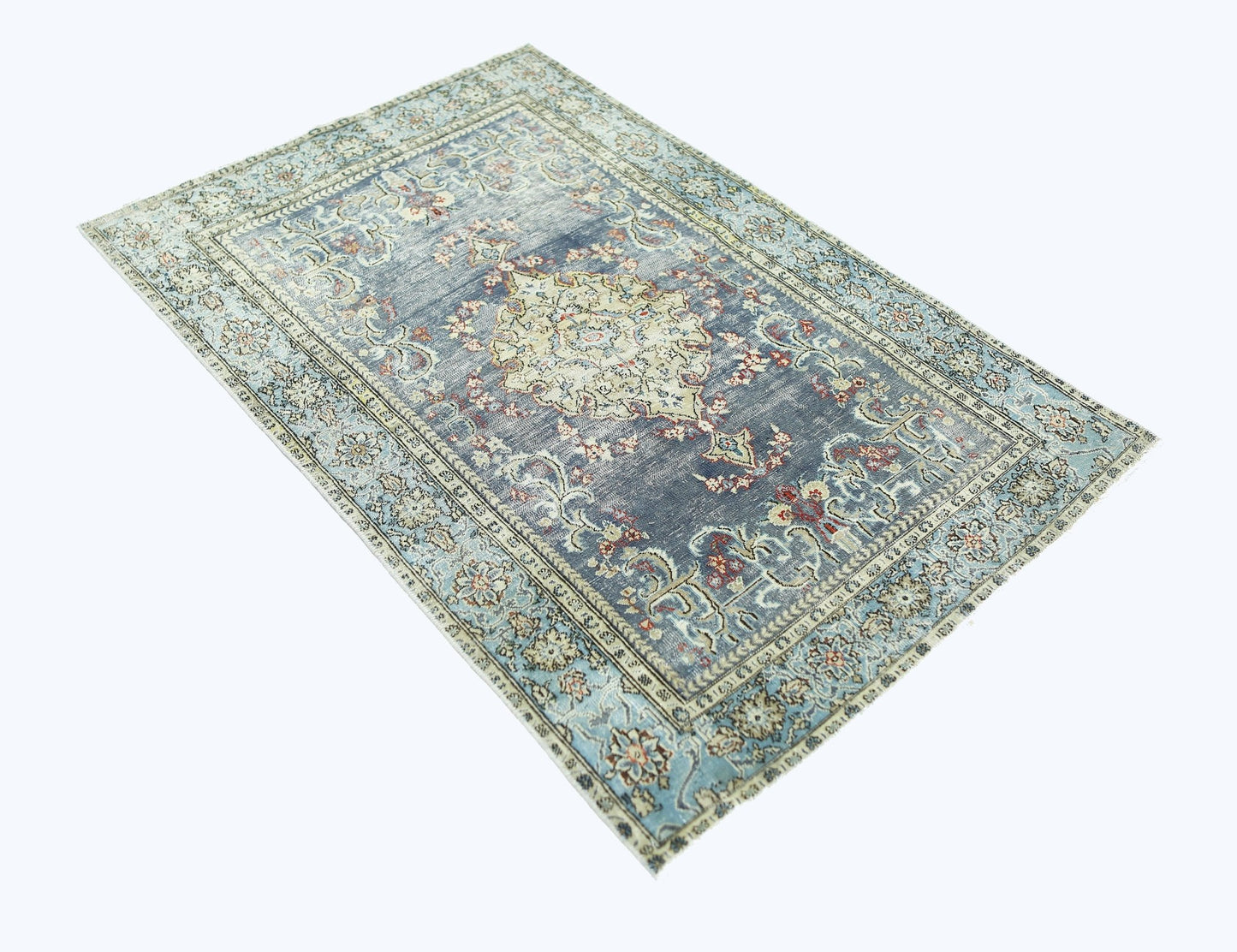 A vintage handmade Persian rug featuring a central floral medallion on a faded blue background.
