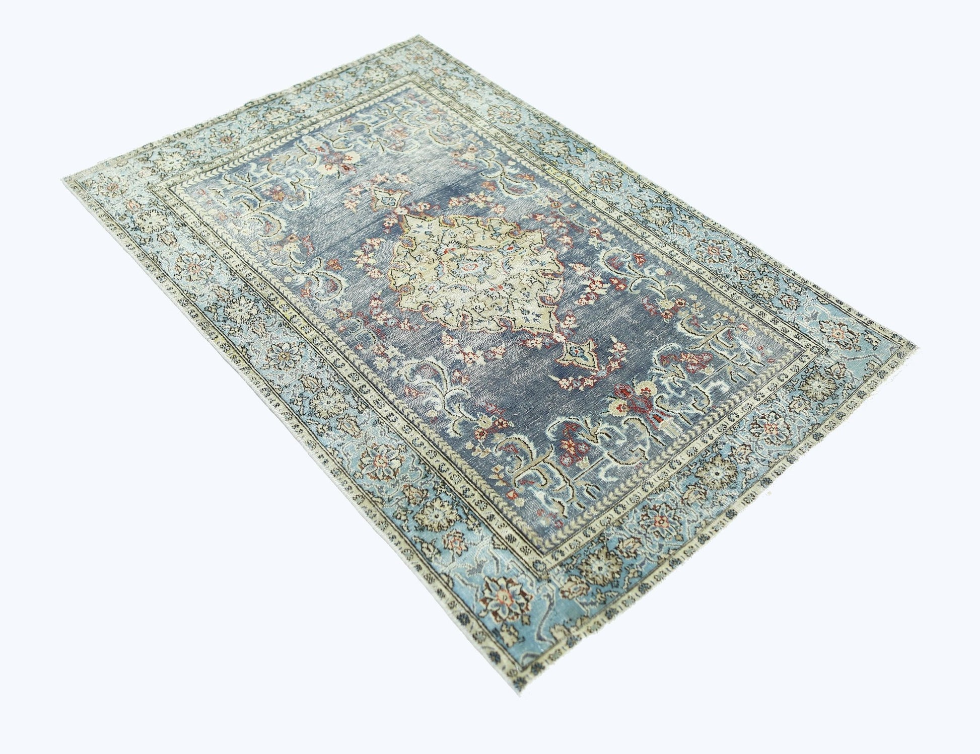 A vintage handmade Persian rug featuring a central floral medallion on a faded blue background.