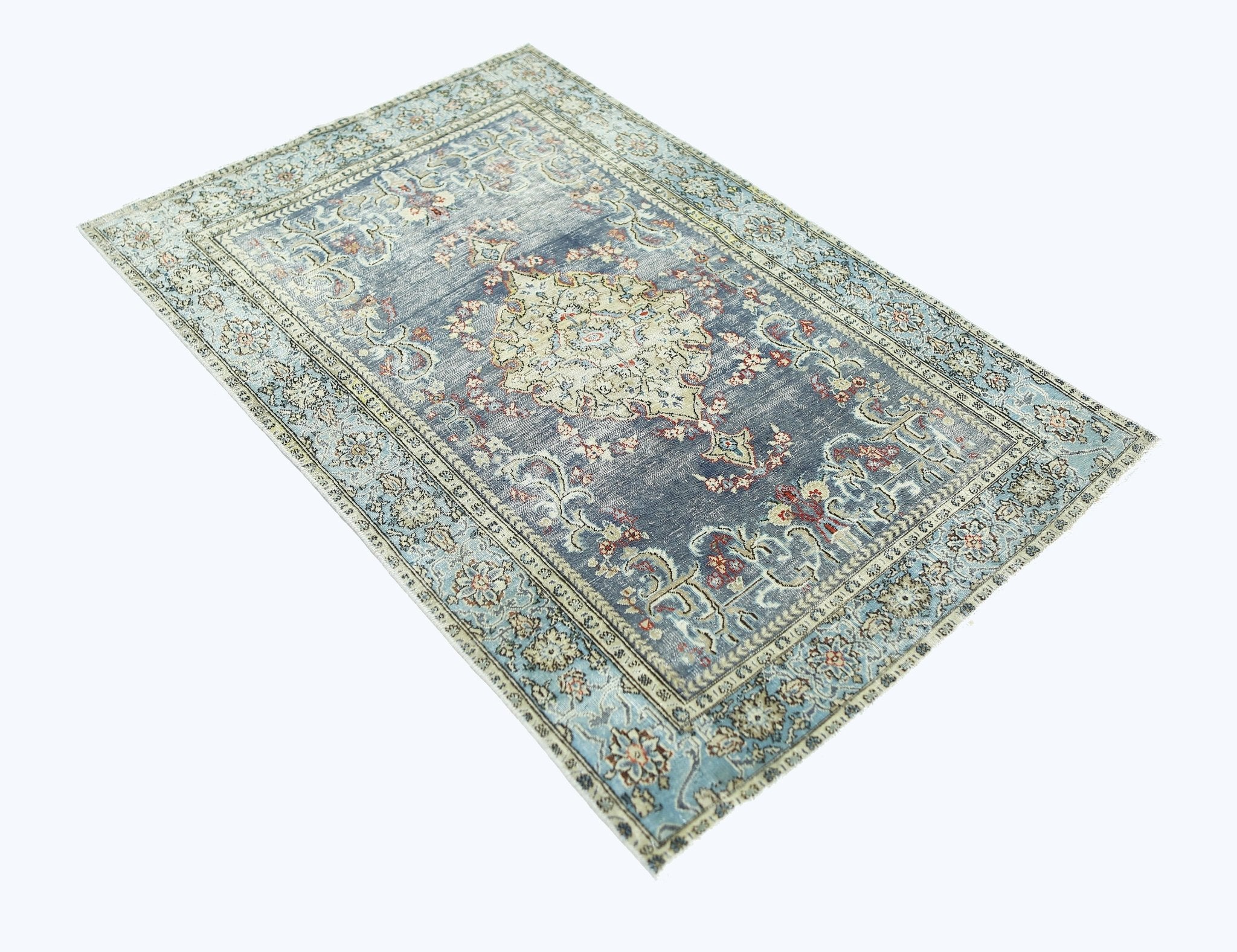A vintage handmade Persian rug featuring a central floral medallion on a faded blue background.