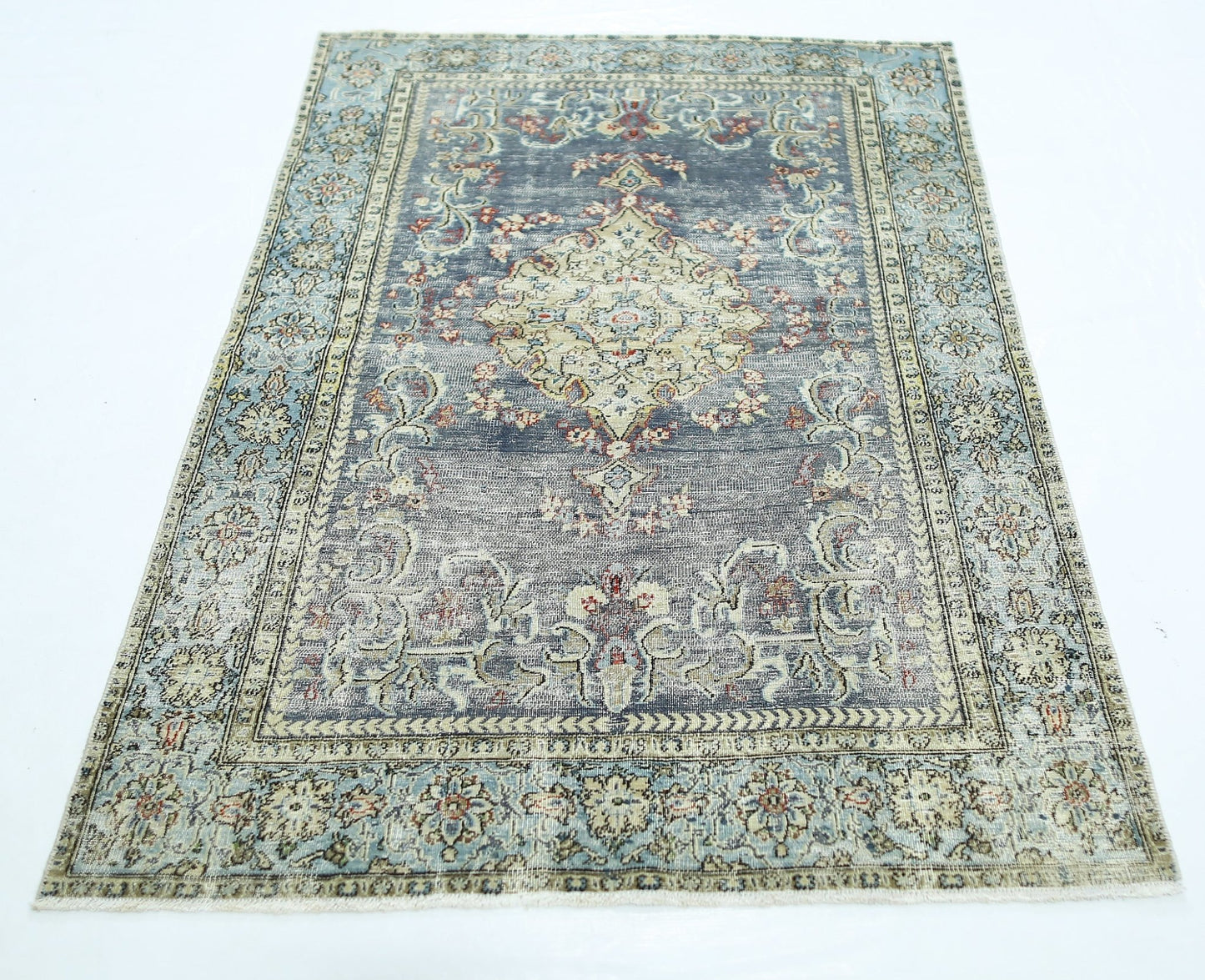 A vintage handmade Persian rug featuring a central medallion on a faded blue and cream field.