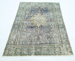 A vintage handmade Persian rug featuring a central medallion on a faded blue and cream field.