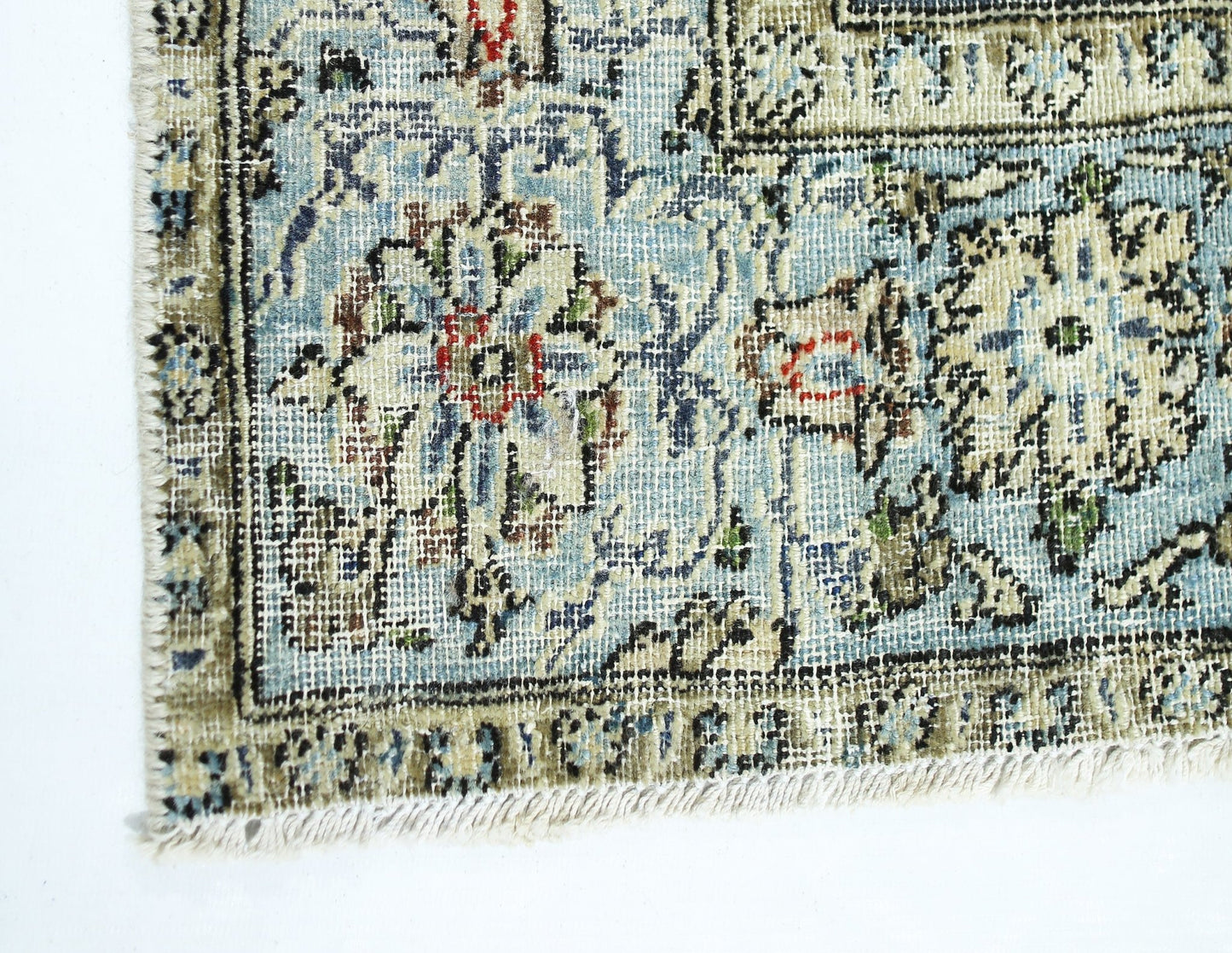 A close-up of a vintage handmade Persian rug featuring intricate floral patterns in blue and beige.