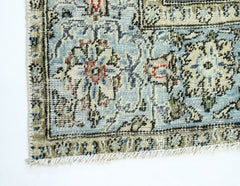 A close-up of a vintage handmade Persian rug featuring intricate floral patterns in blue and beige.