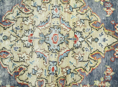 A vintage Persian rug featuring a detailed floral medallion pattern in blue, red, and cream tones.