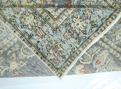 A folded vintage Persian rug featuring intricate floral patterns in blue, cream, and red tones.