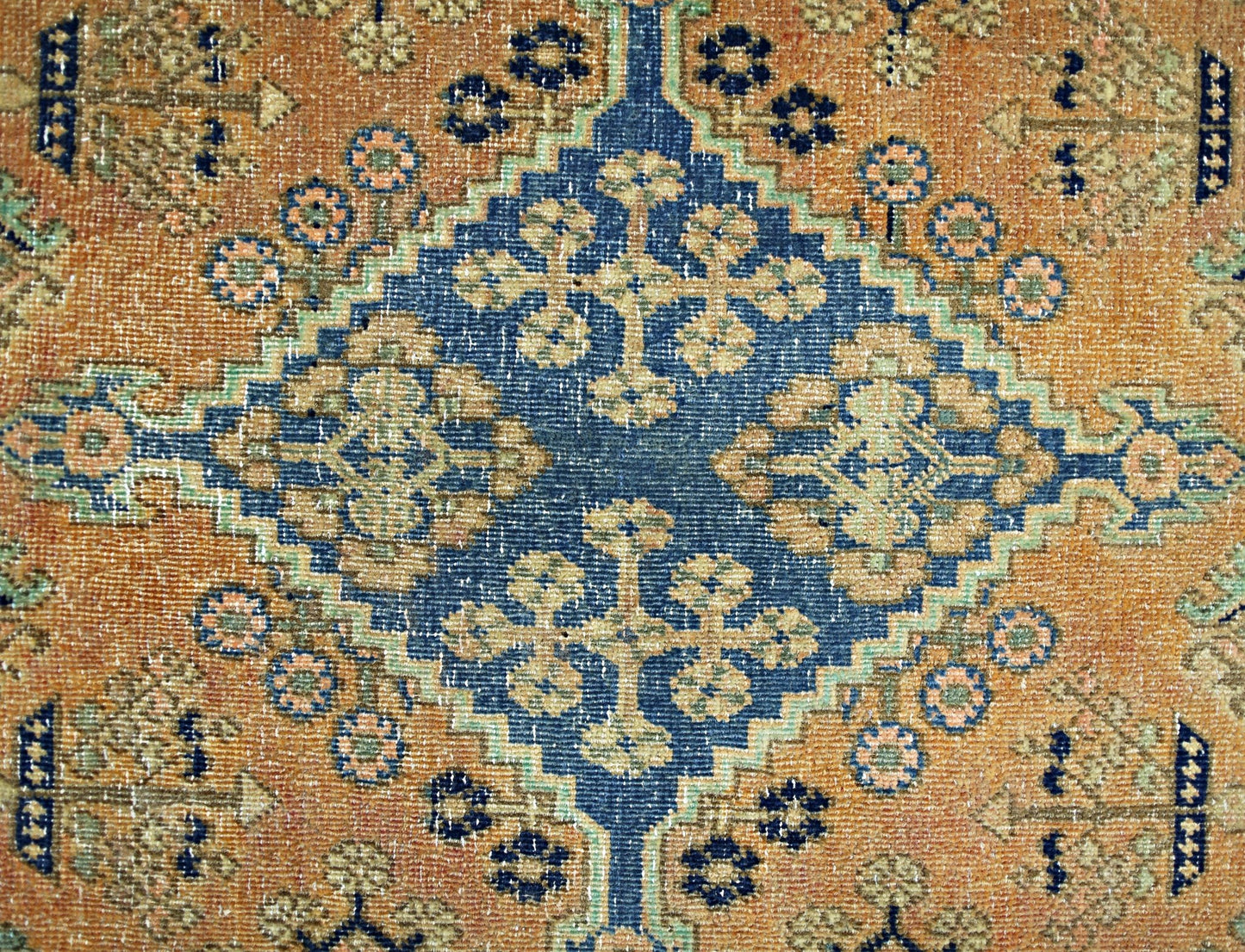 A vintage Persian rug featuring a central blue diamond medallion with intricate floral patterns.