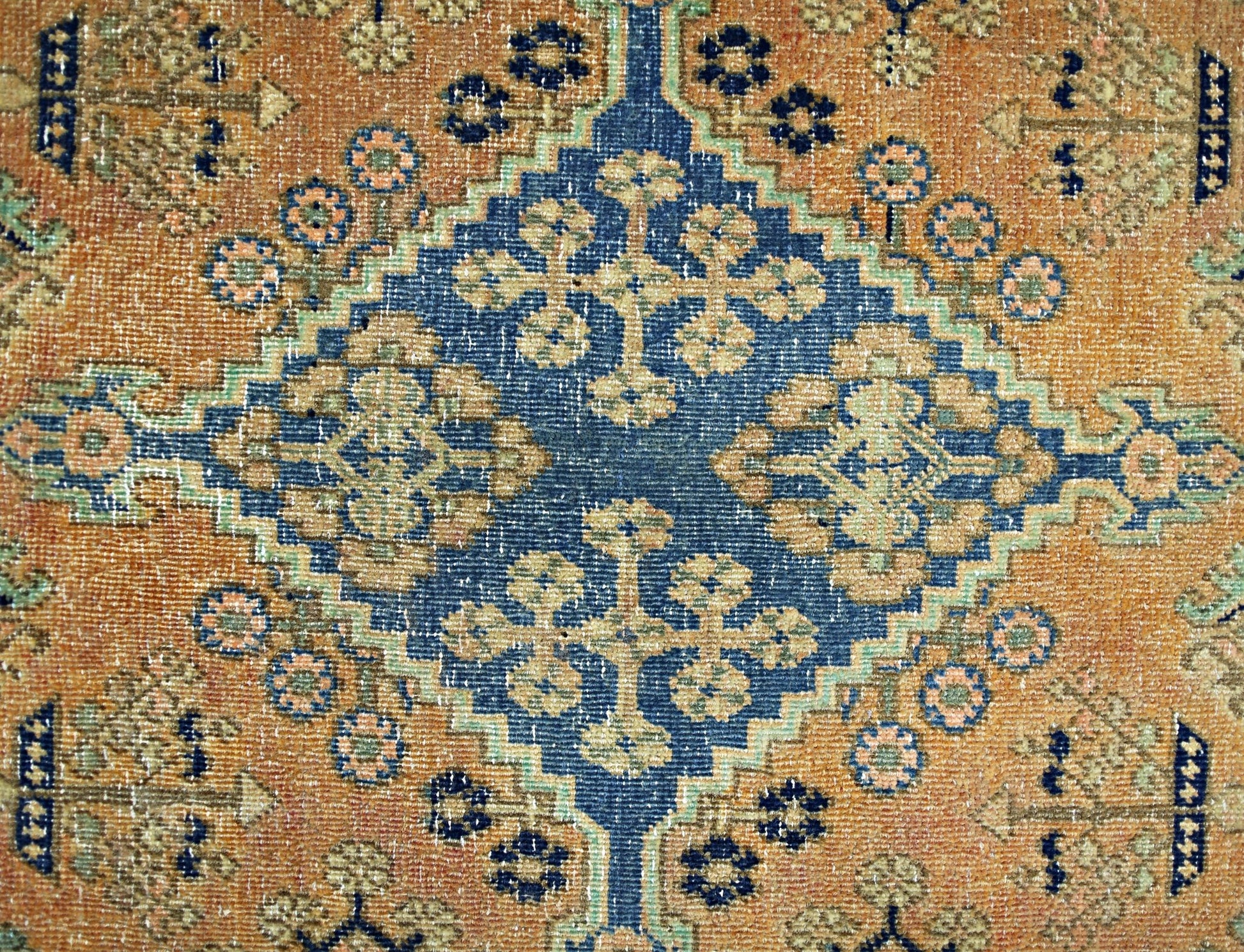 A vintage Persian rug featuring a central blue diamond medallion with intricate floral patterns.