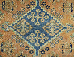 A vintage Persian rug featuring a central blue diamond medallion with intricate floral patterns.