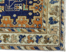 A vintage Persian rug featuring a geometric pattern in blue, orange, and cream tones.