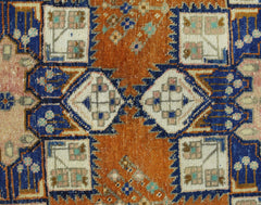 A vintage Persian rug featuring geometric diamond and square motifs in orange, blue, and cream.