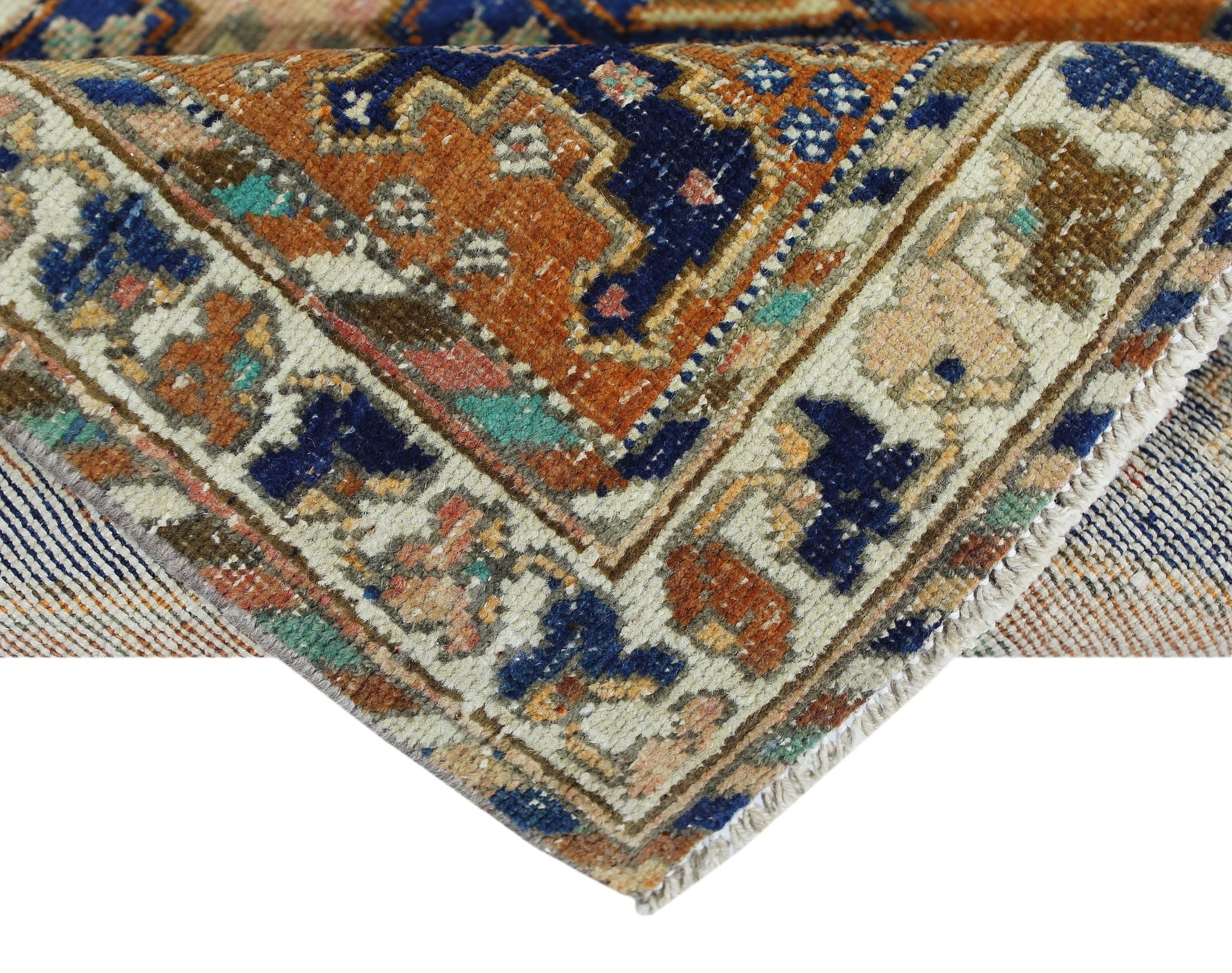A corner view of a vintage Persian rug featuring intricate geometric patterns in blue and orange.