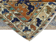 A corner view of a vintage Persian rug featuring intricate geometric patterns in blue and orange.