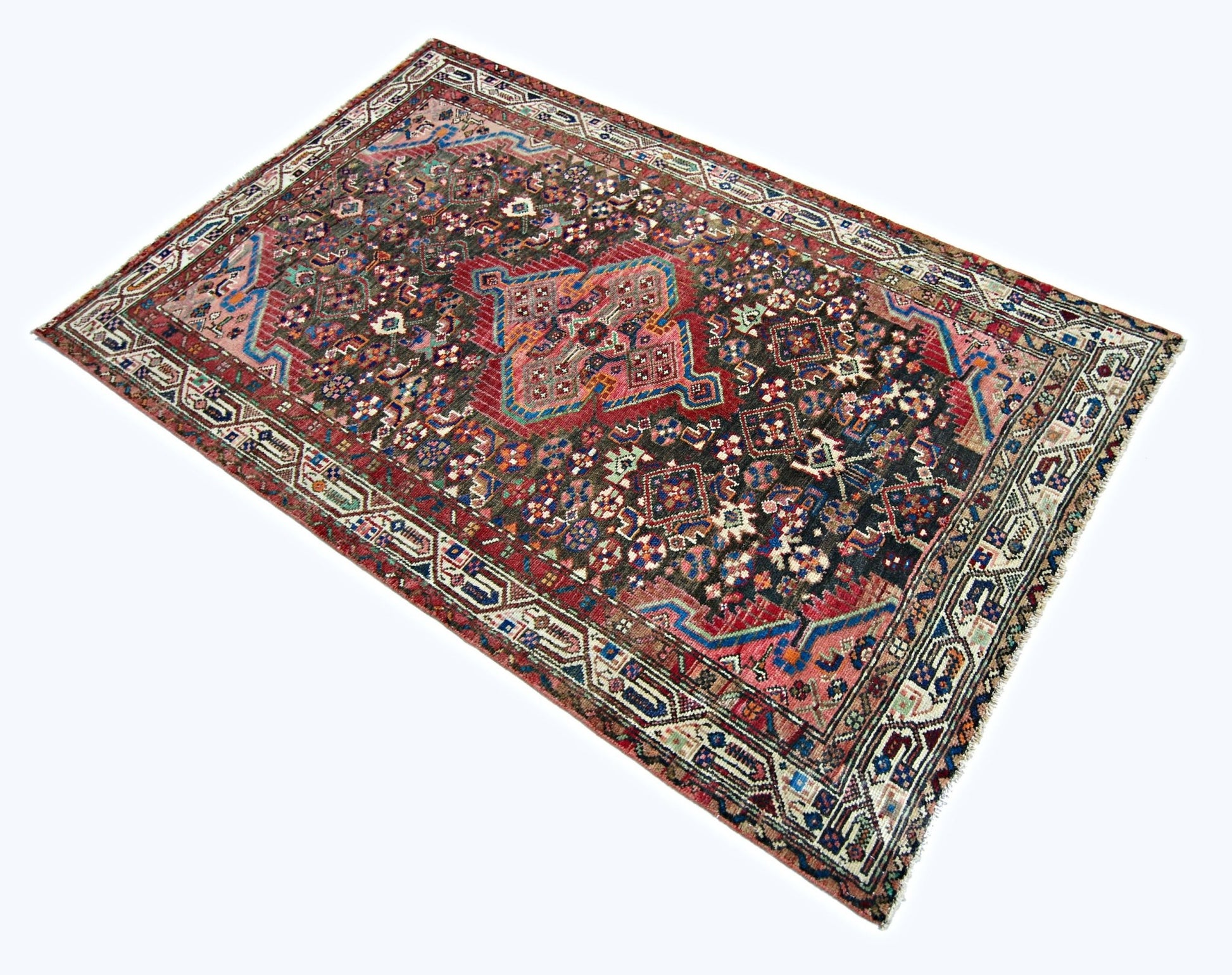 A rectangular vintage Persian rug featuring a dark field with intricate geometric floral patterns.