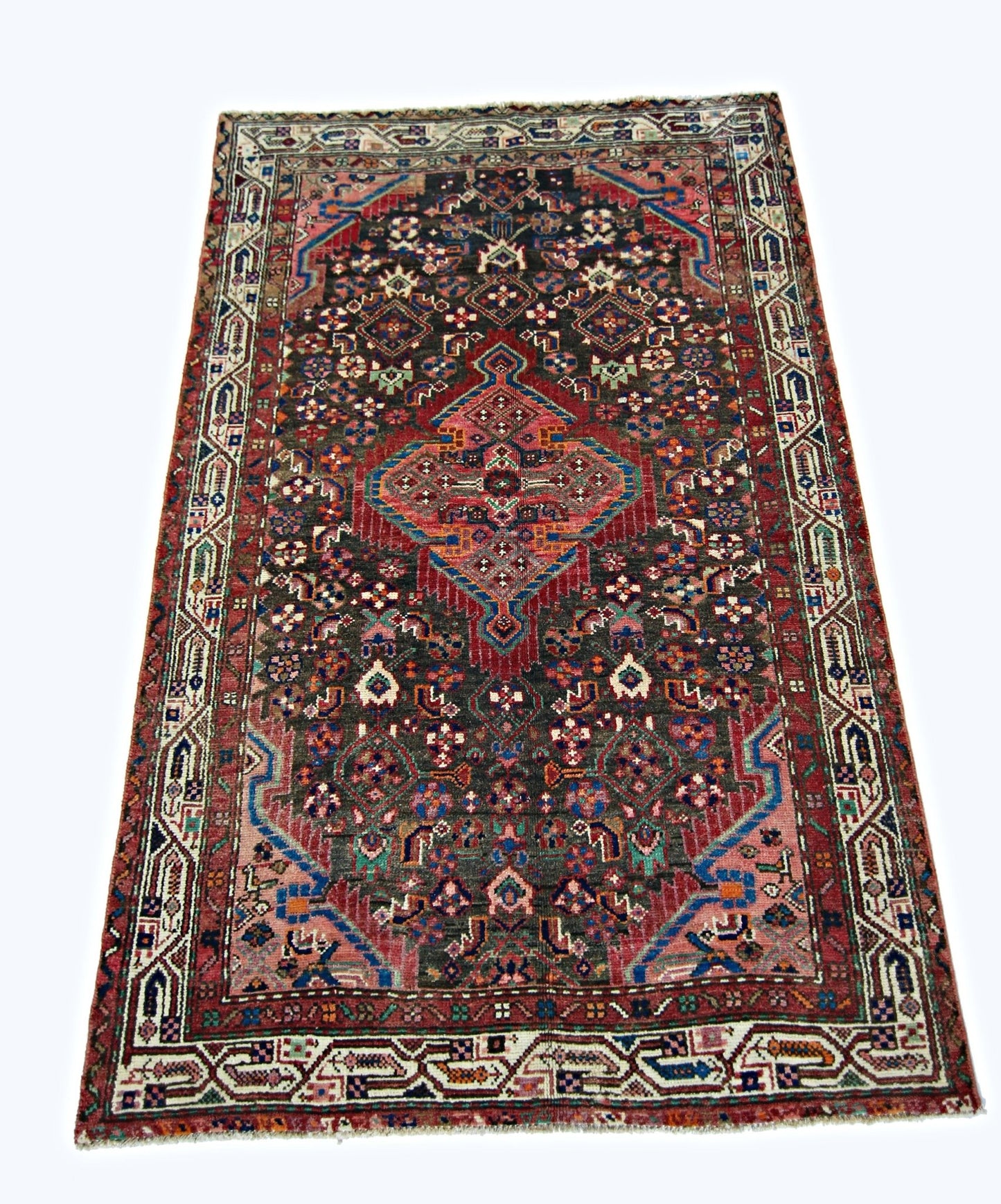 A vintage handmade Persian wool rug featuring a central medallion on a dark patterned field.