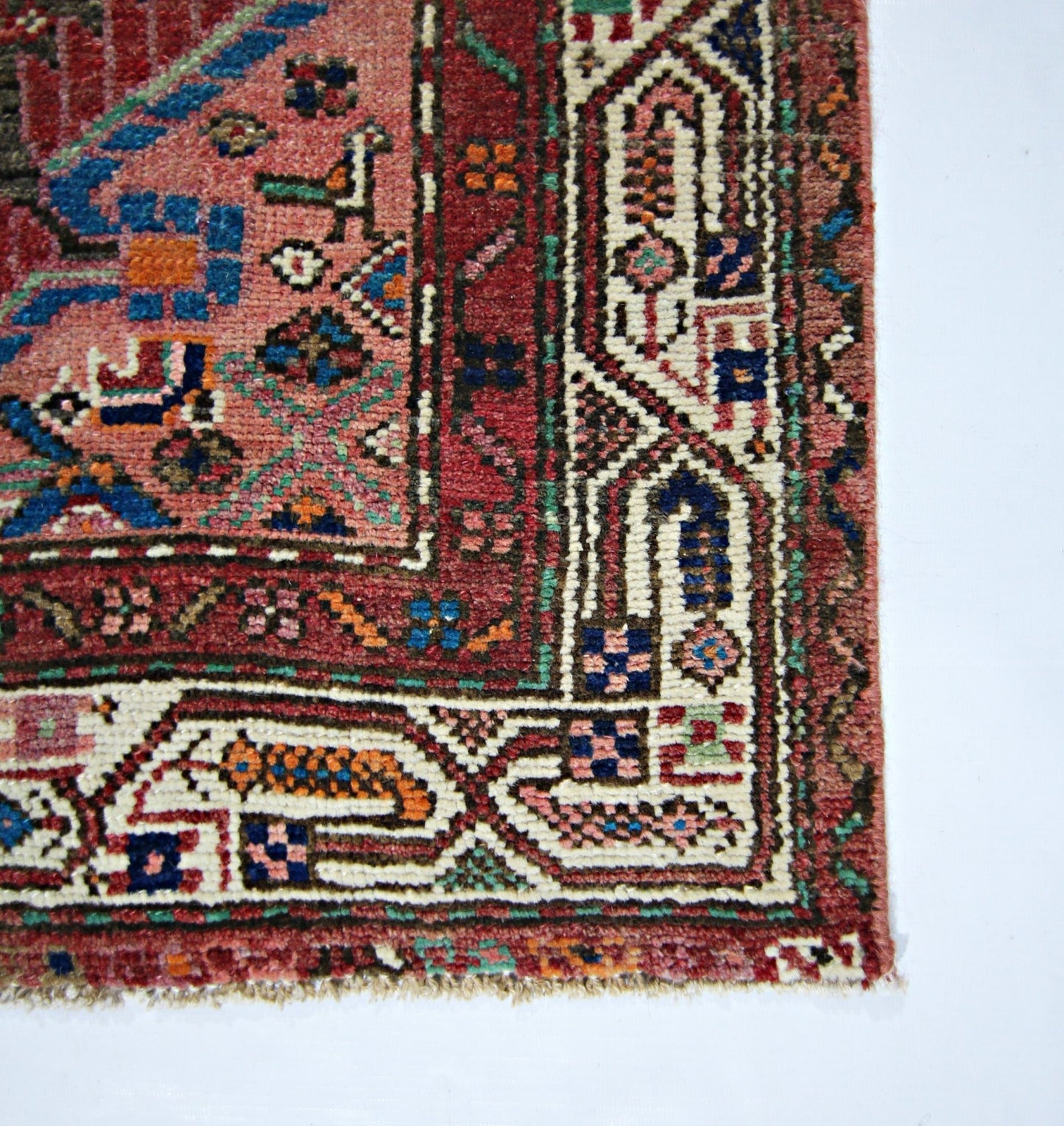 A vintage handmade Persian rug featuring intricate geometric patterns in red, blue, and cream.