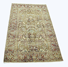 A vintage handmade Persian rug featuring intricate floral patterns in muted earth tones.