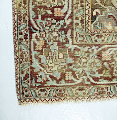 A corner view of a handmade vintage Persian rug featuring intricate floral patterns in red and blue.