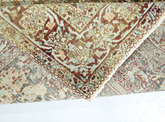 A folded vintage Persian rug featuring intricate patterns in shades of red, blue, and beige.