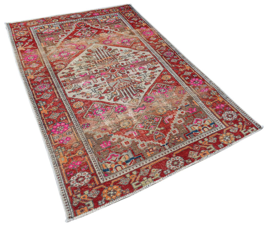 A vintage handwoven Persian rug featuring a central geometric medallion in red, brown, and pink.